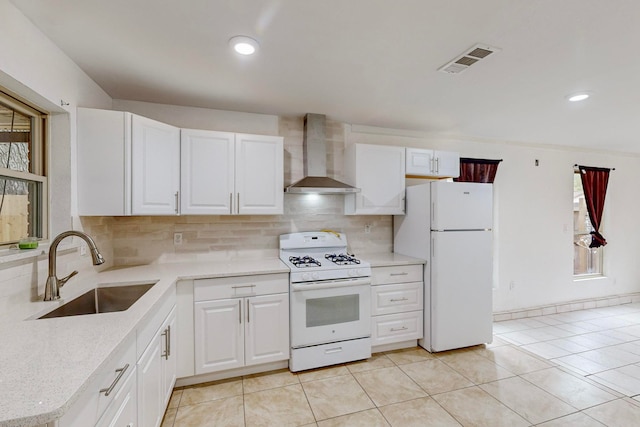 kitchen featuring white appliances, wall chimney range hood, sink, and white cabinets