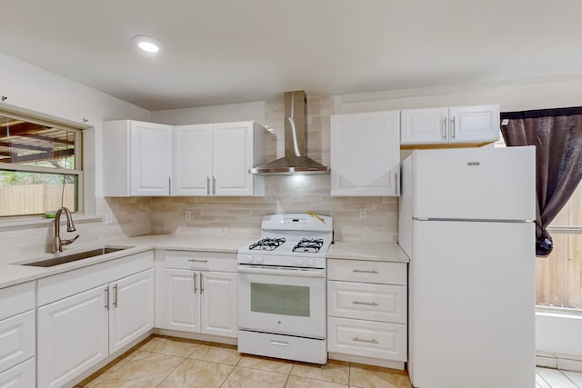 kitchen featuring white appliances, wall chimney exhaust hood, sink, and white cabinets