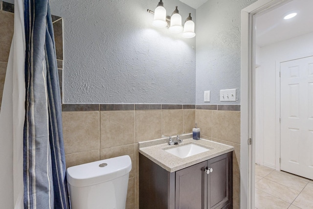 12304 Knight Dr, Balch Springs, TX 75180 - bathroom featuring tile walls, a textured wall, vanity, tile patterned flooring, and wainscoting