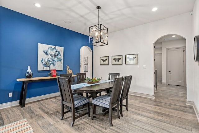 dining area with wood-type flooring and an inviting chandelier