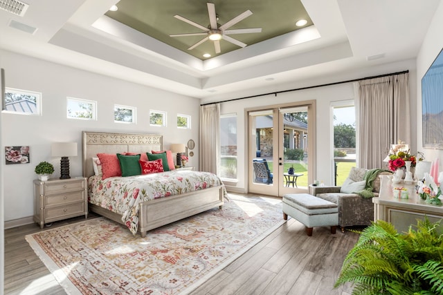 bedroom featuring access to exterior, hardwood / wood-style flooring, a raised ceiling, and ceiling fan