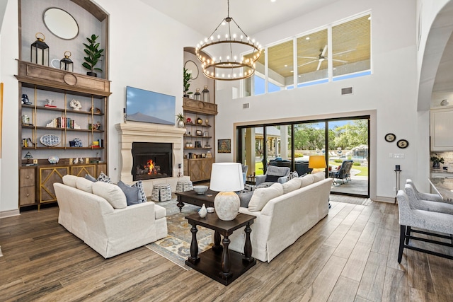 living room with a high ceiling, hardwood / wood-style flooring, and an inviting chandelier