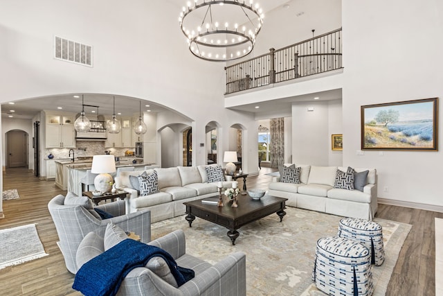 living room featuring a towering ceiling, light hardwood / wood-style flooring, and sink