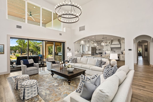 living room with a towering ceiling, hardwood / wood-style floors, and ceiling fan