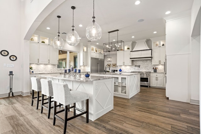 kitchen with premium appliances, a large island, white cabinetry, custom range hood, and dark wood-type flooring