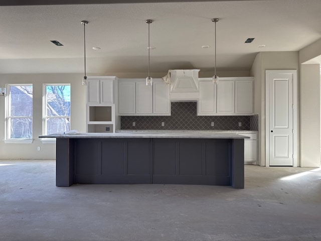 kitchen with custom exhaust hood, a spacious island, hanging light fixtures, decorative backsplash, and white cabinetry