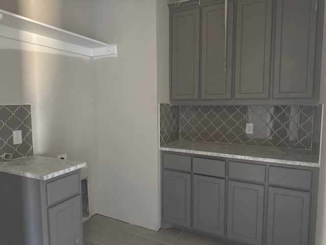 kitchen featuring gray cabinetry, light tile patterned floors, and backsplash