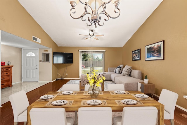 tiled dining area with lofted ceiling and ceiling fan with notable chandelier