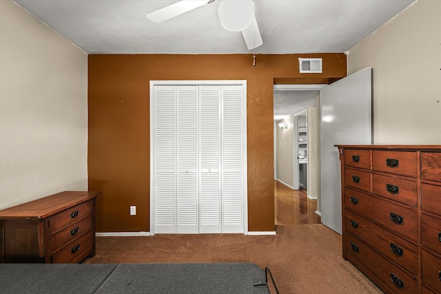 bedroom featuring ceiling fan, a closet, and dark colored carpet