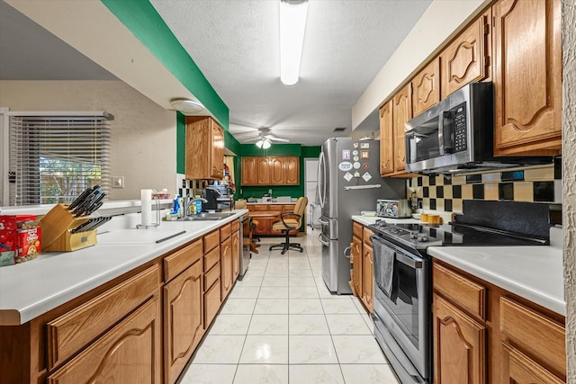 kitchen featuring ceiling fan, sink, tasteful backsplash, a textured ceiling, and appliances with stainless steel finishes