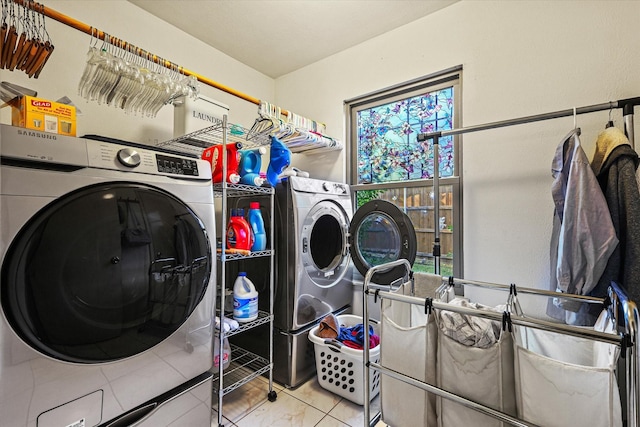 clothes washing area with light tile patterned floors, washing machine and dryer, and a healthy amount of sunlight