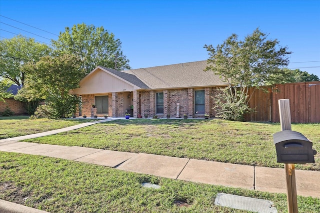 ranch-style house featuring a front yard, brick siding, and fence