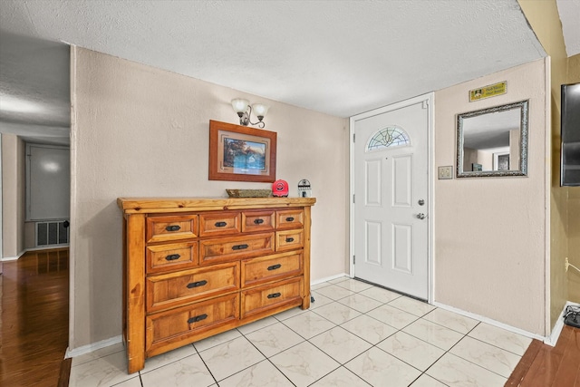 entryway featuring visible vents, a textured ceiling, and baseboards