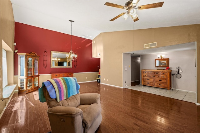 living room featuring ceiling fan with notable chandelier, light wood-style flooring, visible vents, and baseboards