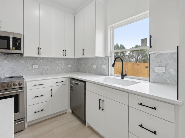 kitchen featuring decorative backsplash, sink, white cabinetry, and stainless steel appliances