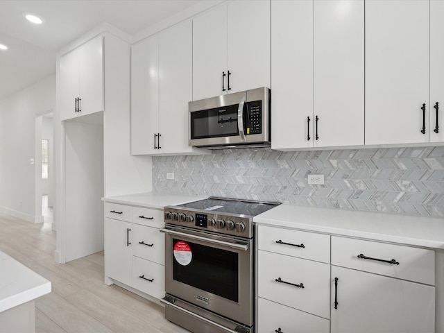 kitchen featuring white cabinets, light hardwood / wood-style floors, backsplash, and appliances with stainless steel finishes