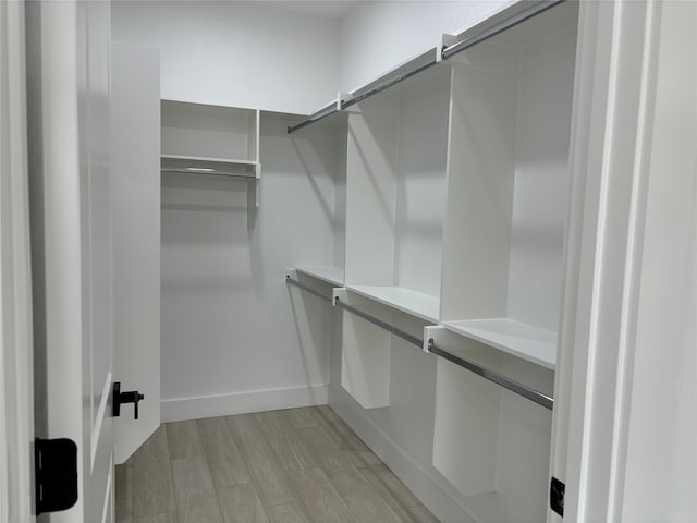 walk in closet with light hardwood / wood-style flooring