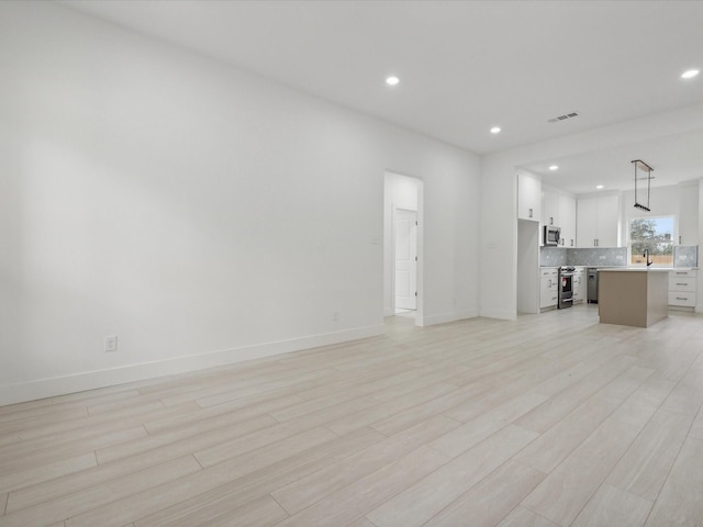 unfurnished living room with light hardwood / wood-style floors and sink