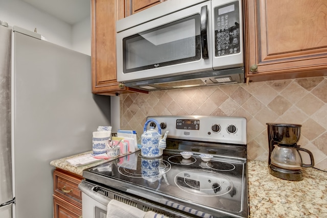 kitchen featuring appliances with stainless steel finishes, light stone counters, and backsplash