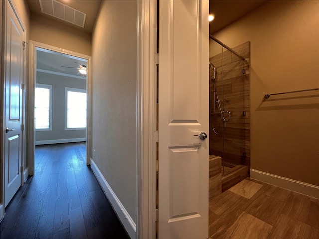 interior space with ceiling fan, hardwood / wood-style flooring, walk in shower, and ornamental molding