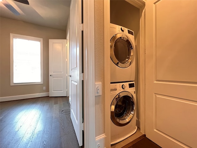 washroom featuring ceiling fan, stacked washer and clothes dryer, and dark hardwood / wood-style flooring