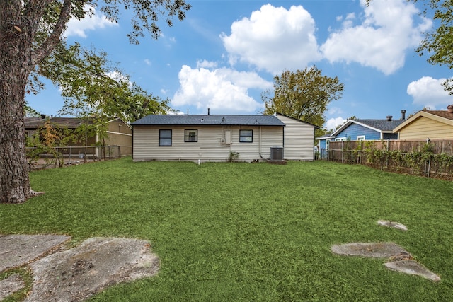 rear view of house with central air condition unit and a lawn