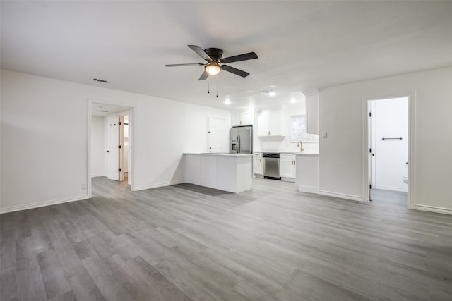 unfurnished living room with sink, light wood-type flooring, and ceiling fan