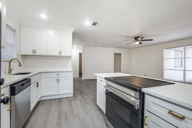 kitchen with white cabinetry, stainless steel appliances, sink, and light wood-type flooring