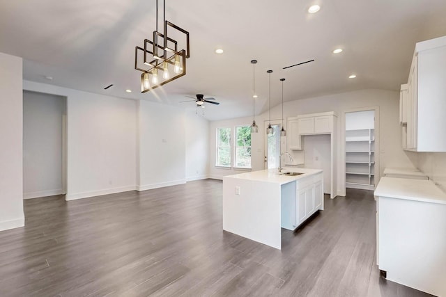 kitchen featuring ceiling fan, a kitchen island with sink, hanging light fixtures, white cabinetry, and dark hardwood / wood-style flooring