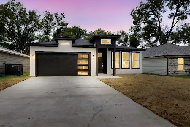 view of front of home with stucco siding, driveway, and a garage