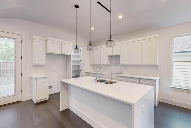 kitchen with dark wood finished floors, a center island with sink, pendant lighting, white cabinetry, and a sink