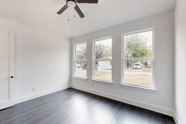 spare room featuring dark wood-style floors, a ceiling fan, and baseboards