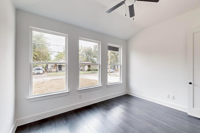 empty room with dark wood-type flooring, a ceiling fan, baseboards, and vaulted ceiling