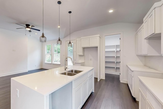 kitchen with a sink, white cabinetry, dark wood-style flooring, and vaulted ceiling