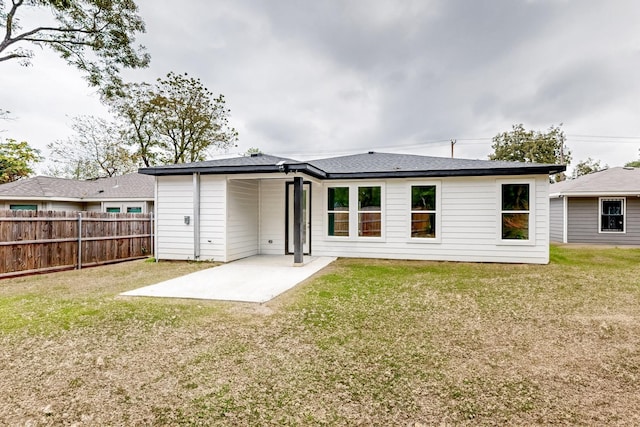 rear view of house with a patio, a lawn, and fence