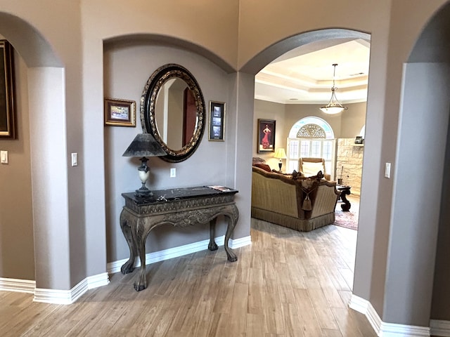 hall with wood-type flooring and a tray ceiling