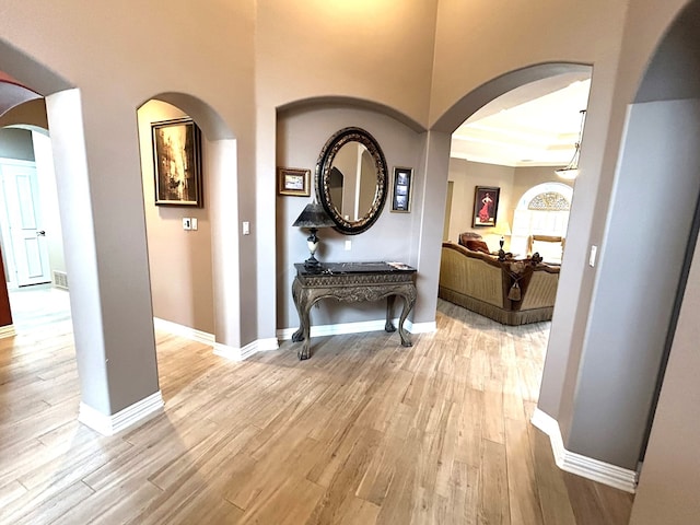 corridor with light hardwood / wood-style floors and a raised ceiling