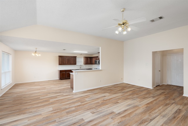 unfurnished living room with a textured ceiling, light wood-type flooring, and ceiling fan with notable chandelier