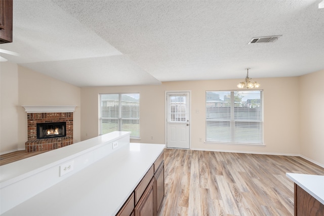 kitchen featuring light hardwood / wood-style floors, a textured ceiling, a healthy amount of sunlight, and decorative light fixtures