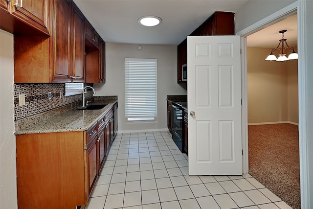 kitchen with light stone counters, an inviting chandelier, black appliances, sink, and light colored carpet