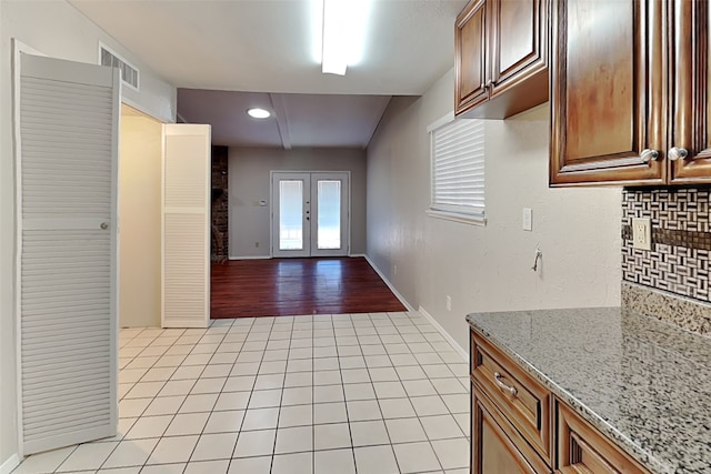 kitchen featuring light stone counters, decorative backsplash, and light hardwood / wood-style floors