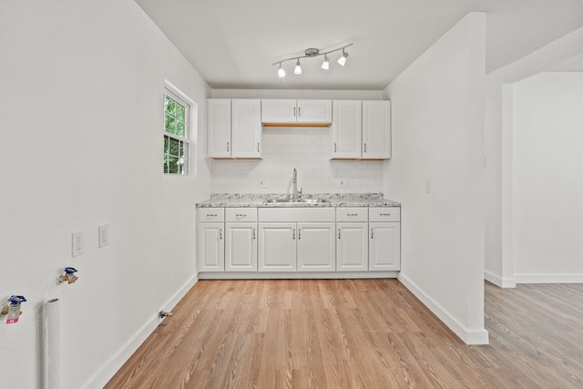 kitchen with decorative backsplash, white cabinetry, sink, and light wood-type flooring