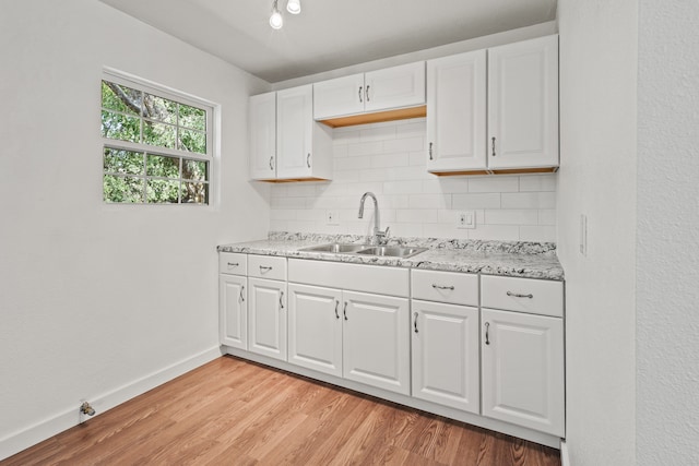 kitchen featuring white cabinetry, light hardwood / wood-style floors, sink, and backsplash