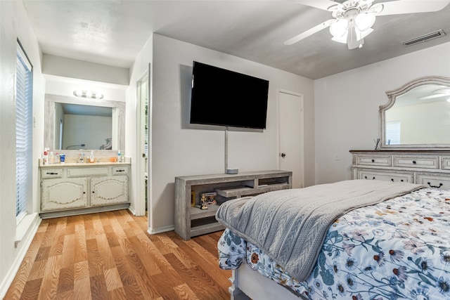 bedroom with ensuite bathroom, light hardwood / wood-style floors, and ceiling fan