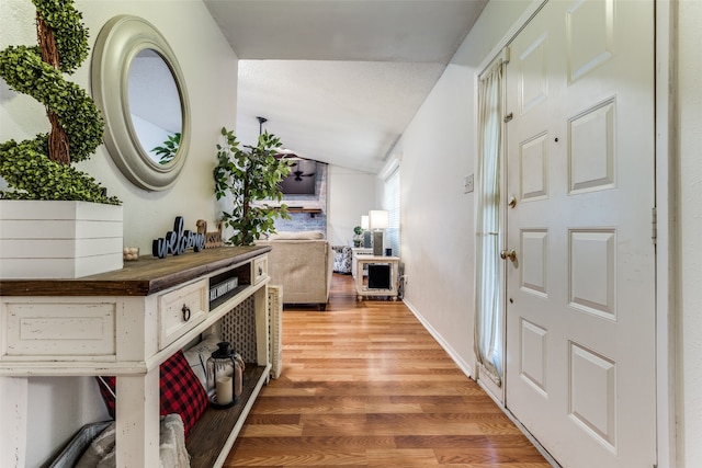 hall with hardwood / wood-style floors and vaulted ceiling