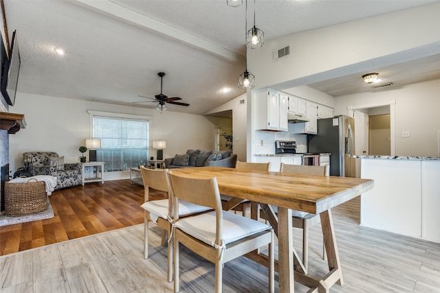 dining room with light hardwood / wood-style floors, lofted ceiling, a textured ceiling, and ceiling fan