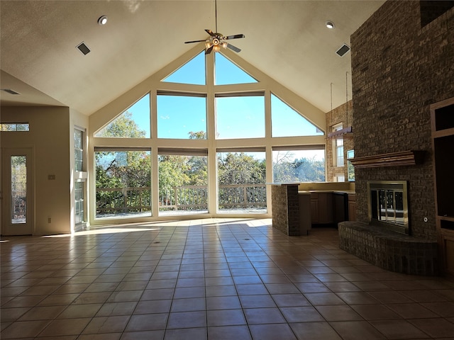 unfurnished living room featuring tile patterned floors, a wealth of natural light, a fireplace, and high vaulted ceiling