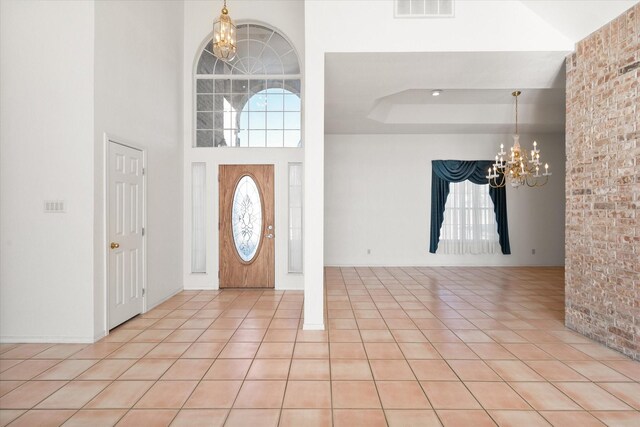 foyer entrance with light tile patterned floors, a towering ceiling, and an inviting chandelier