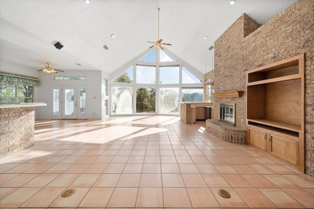 unfurnished living room with ceiling fan, french doors, high vaulted ceiling, a fireplace, and light tile patterned flooring