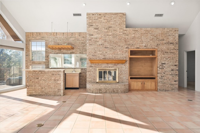 unfurnished living room with a towering ceiling, a fireplace, and light tile patterned floors